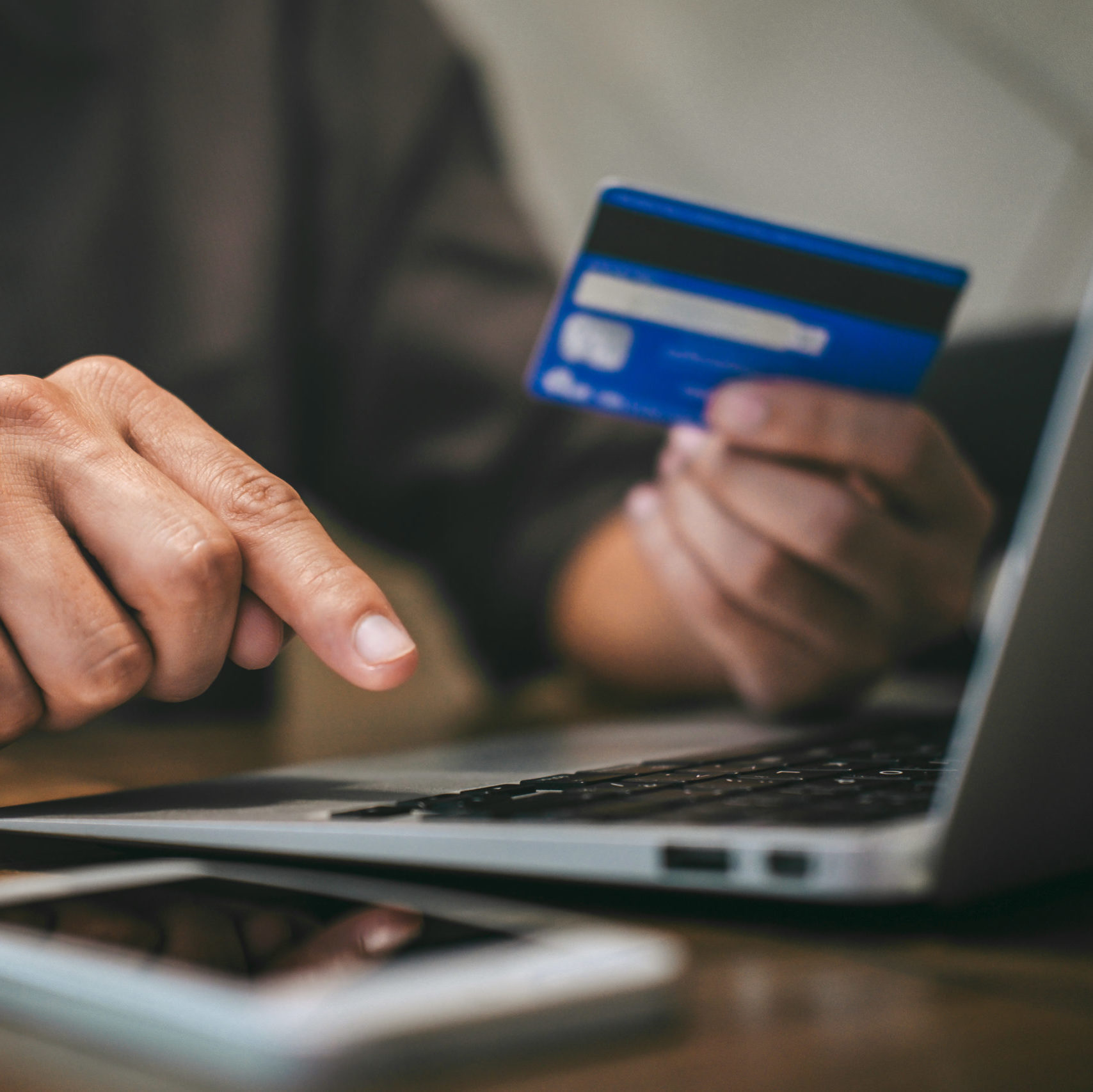 man typing on computer keyboard holding credit card