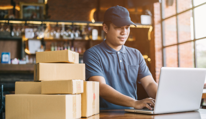 man in a small business making an online purchase with parcels on the table